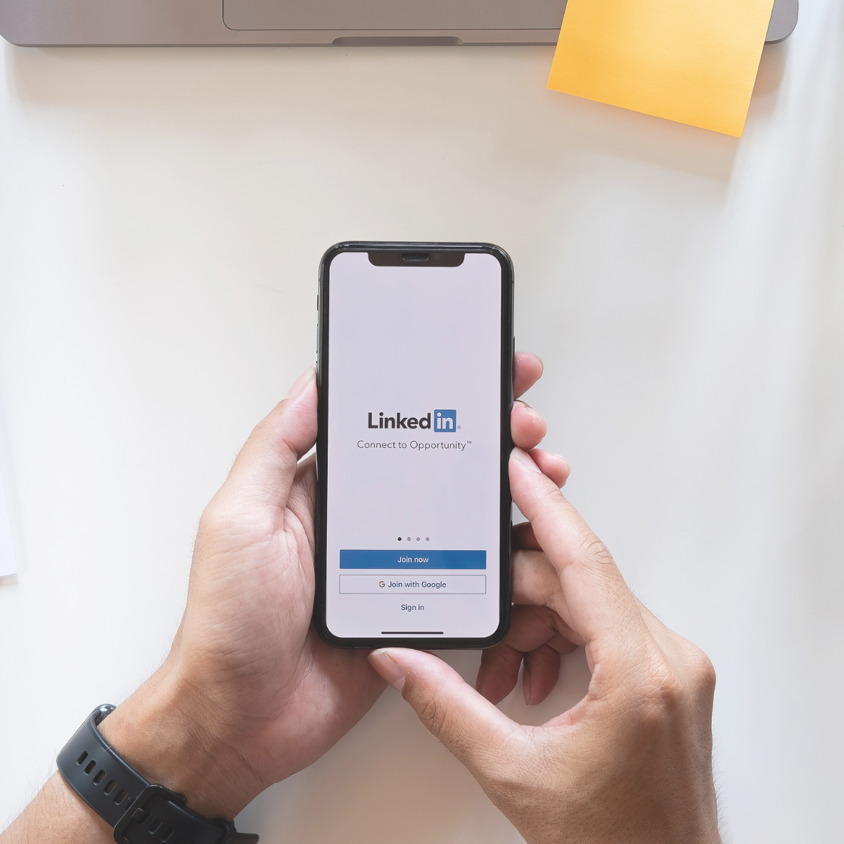 Person holding iPhone with LinkedIn sign in page showing on phone screen