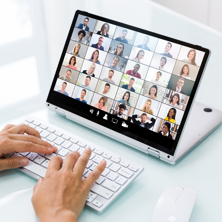 Person sitting at computer with computer screen showing a virtual meeting