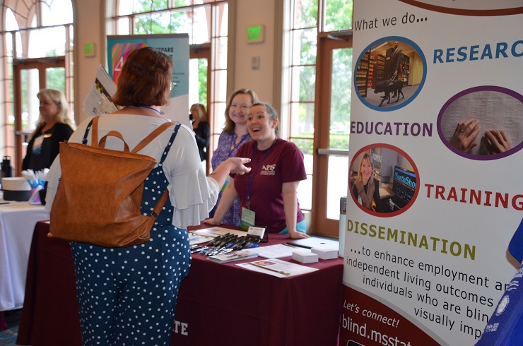 Anne and Karla talking with an attendee at the CHARGE conference