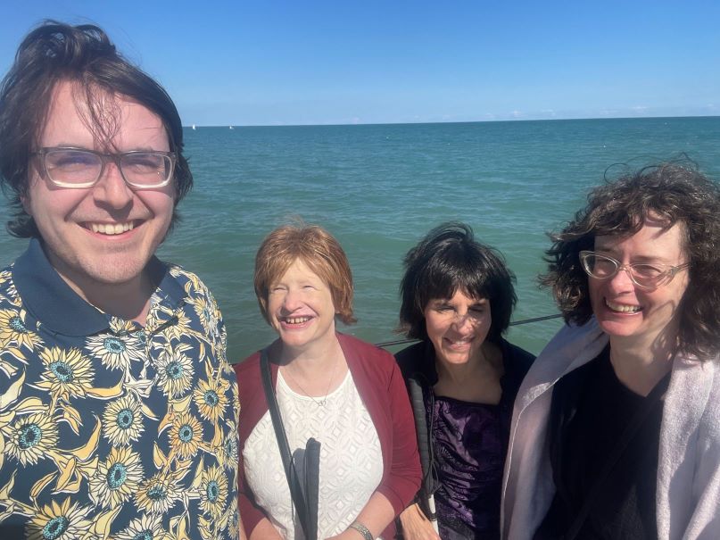 From left to right, Isaiah, Jennifer, Kendra and Polly smile while standing next to a blue lake.