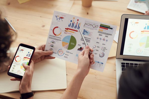 Two hands holding a paper with graphs and charts.