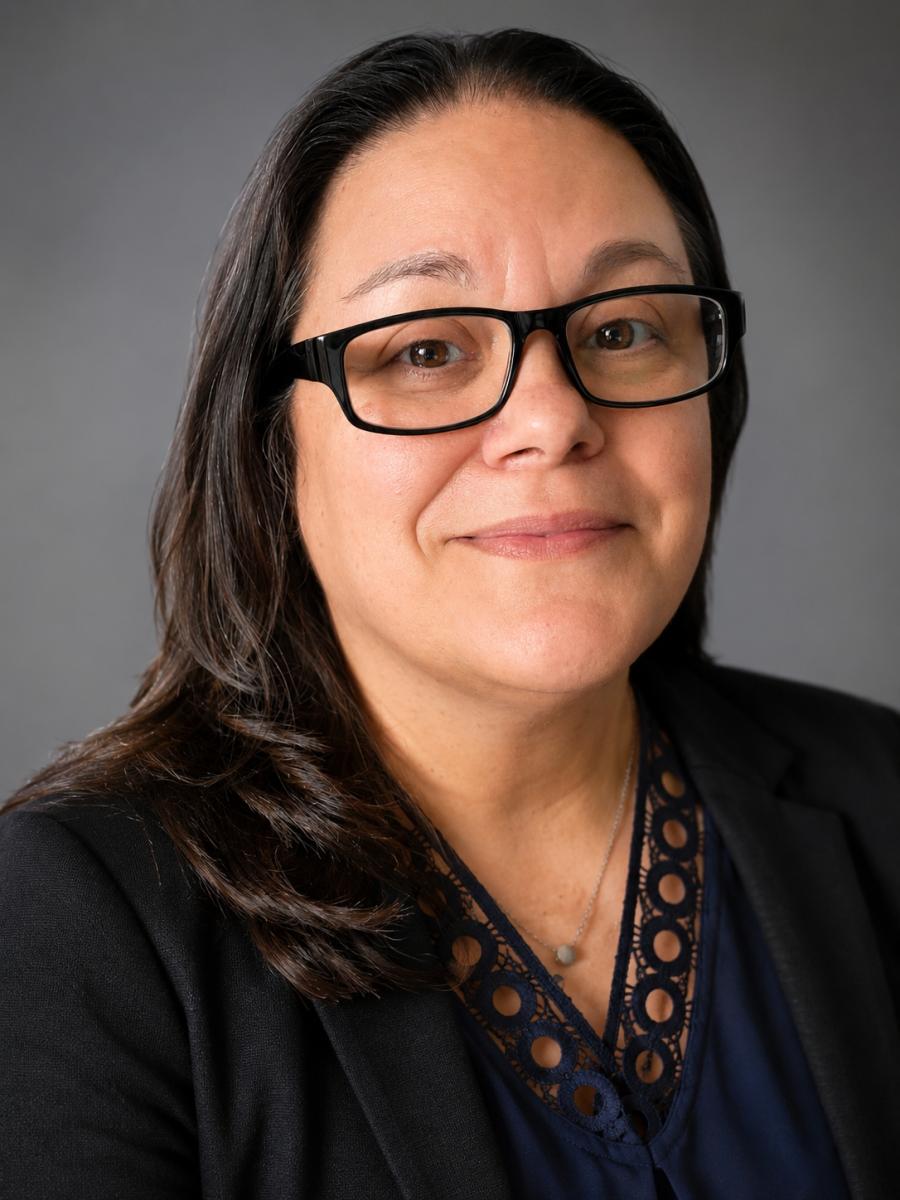 Headshot of Lea. She is smiling, wearing glasses and is wearing a black professional top.