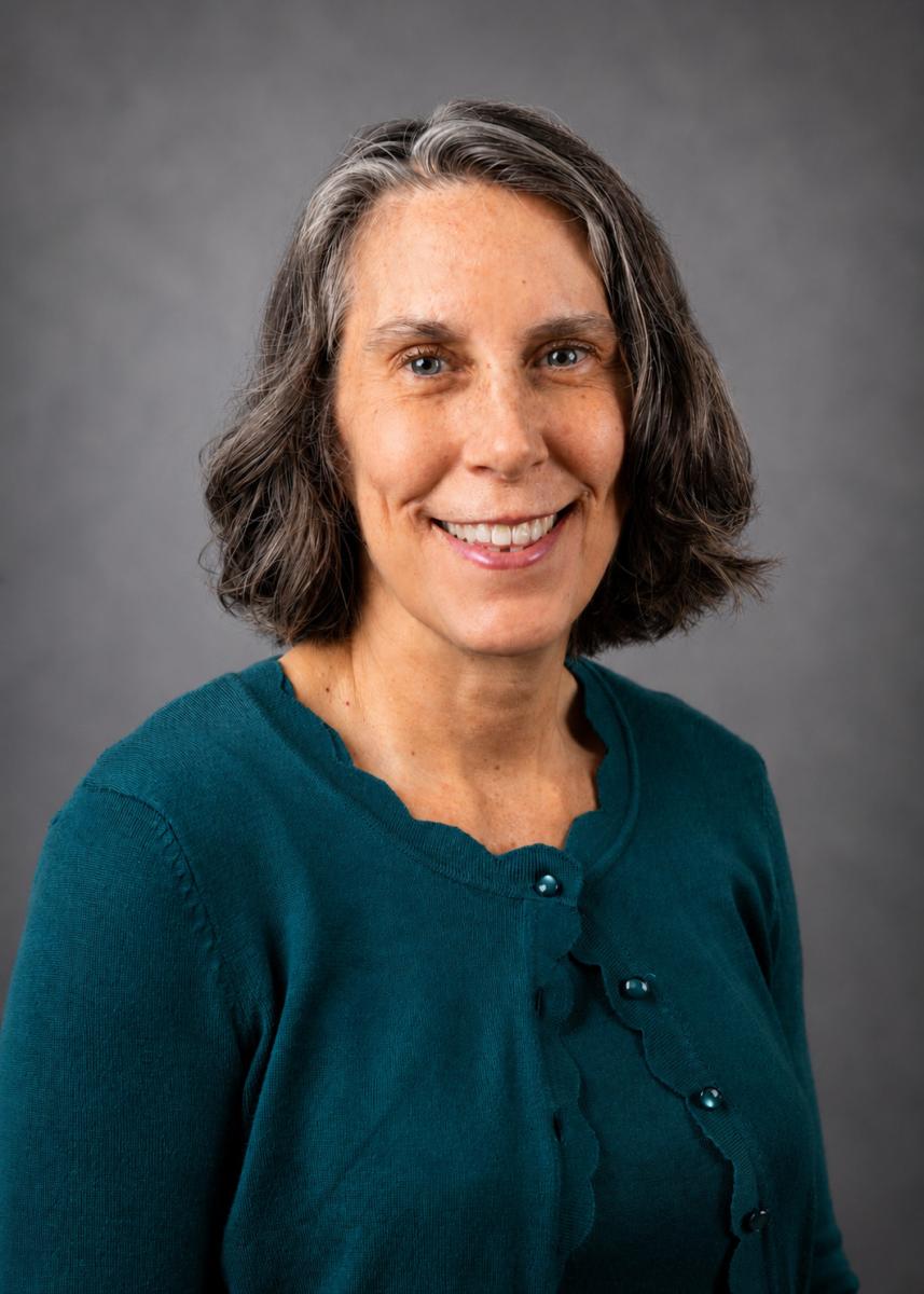 Headshot of Michele. Michele is wearing a teal blouse and is smiling at the camera.