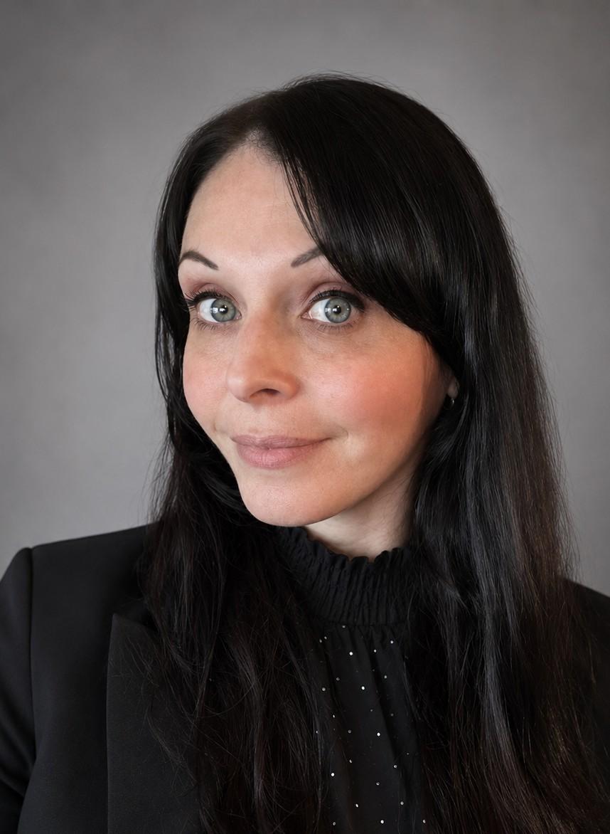 Headshot of Stephanie. Stephanie is wearing a black blouse and is smiling.